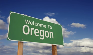 Welcome to oregon green road sign over blue sky with some clouds