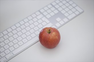 Symbol photo on the topic 'Äô Healthy eating at work 'Äô. An apple lies next to a keyboard on an