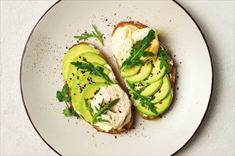 Sandwich with cream cheese, sliced avocado and boiled egg, arugula, on grainy bread, homemade,