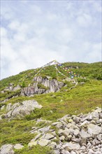 Prayer flags fluttering on a rocky mountainside under a cloudy sky, Little Tibet, Zillertal,