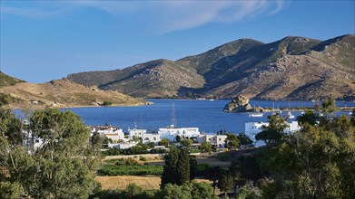 View of a bay and a picturesque coastal town surrounded by mountains and green vegetation under a