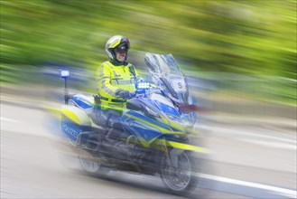 Policeman on a motorbike driving fast along the road, the speed is emphasised by the motion blur,