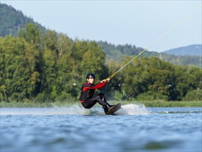 Young man doing sports with wakeboard in lake, water sports, water skiing in wakepark, Stráž pod