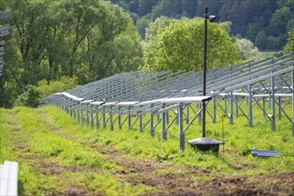 Solar installations in a green, rural environment with metal structures and trees, construction of