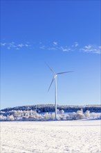 Wind turbine on a field in a rural landscape with snow and frost a cold sunny winter day. Sweden