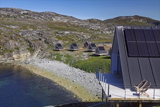 Modern wooden cabins with solar panels on a rocky coastal landscape in nature, Tourimus, Ilimanaq,