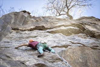 A man climbs a rugged rock face in nature, embracing the thrill of extreme sports. His