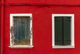 Bright red house wall with two windows, one renovated, Burano, Venice, Veneto, Italy, Europe