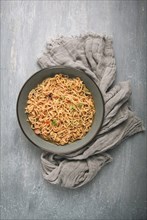 Instant noodles, in a bowl, on a gray table, top view, no people