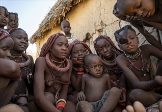 Group of Himba children and young woman look at pictures on a camera, near Opuwo, Kaokoveld,