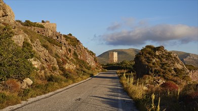 A picturesque road leading to a tower on a hill under warm twilight, residential tower, hotel, Mani