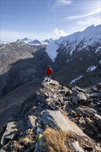 Mountaineer standing on a rock, surrounded by an impressive mountain landscape with snow-covered