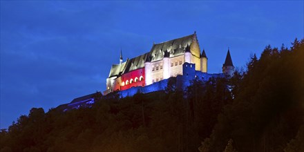 Vianden Castle, hilltop castle illuminated in the colours of the Luxembourg flag for the bank