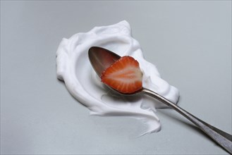 Strawberry with cream on a spoon