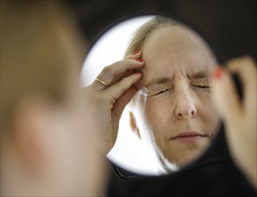 Symbolic photo on the subject of migraines and headaches. A woman rubs her aching head with her