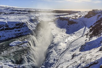 Large waterfall in a gorge in the snow, winter, sunny, backlight, spray, Gullfoss, Golden Circle,