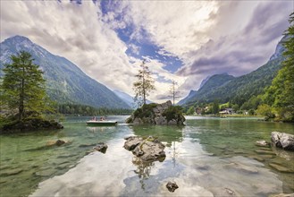 Hintersee with rocks and trees in the foreground, surrounded by mountains after sunset with