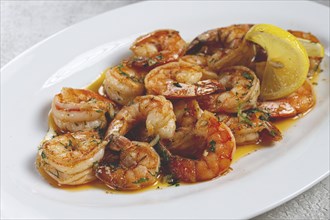 Fried tiger prawns, jumbo, in garlic sauce, in butter, with herbs, on a white plate, homemade, no