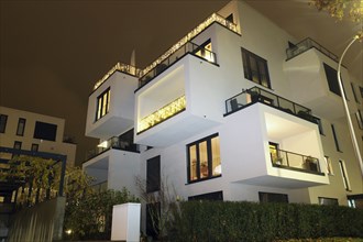 Symbolic image of modern living: Night shot of a modern apartment building in urban style