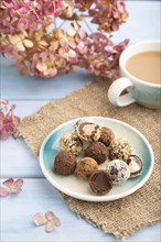 Chocolate truffle candies with cup of coffee on a blue wooden background and linen textile. side