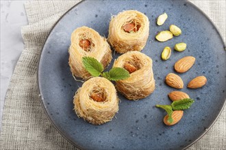 Kunafa, traditional arabic sweets in blue ceramic plate on a gray concrete background. side view,