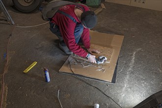 Young man working with an angle grinder in his workshop in the evening, Mecklenburg-Vorpommern,