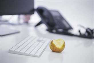 Symbol photo on the topic 'Äô Healthy eating at work 'Äô. An apple lies next to a keyboard on an