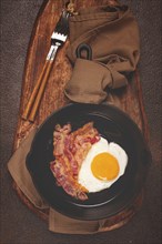 Fried egg with bacon, in a cast-iron pan, breakfast, top view, close-up, homemade, no people