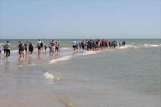 Ttourists standing at the northern tip of Denmark where the Baltic Sea and North Sea meet at Skagen