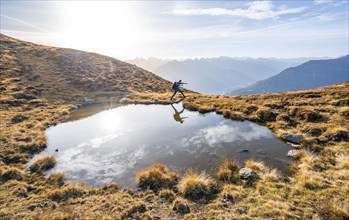 Mountaineer jumping, reflected in a small mountain lake on the Krahberg, mountain panorama in