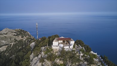 Drone shot, A building with an antenna on a hill surrounded by trees and the sea, Panagia Kyra