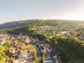 Aerial view of a riverside town surrounded by green hills and forests on a sunny day, Calw, Black