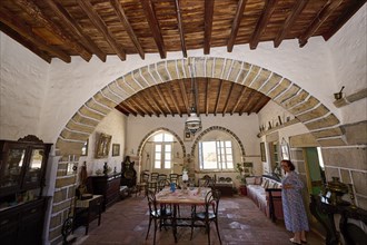 Dining room with round arch, rustic wooden floors, antique furniture and bright natural light. One