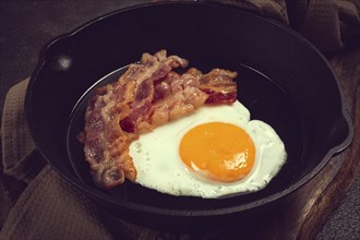 Fried egg with bacon, in a cast-iron pan, breakfast, top view, close-up, homemade, no people