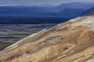 Geothermal field and sulphur springs in front of mountain landscape, clouded, Namafjall, Myvatn,