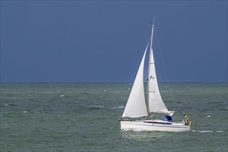 Sailboat sailing along the North Sea coast in Zeeland, Netherlands on a rainy day during bad