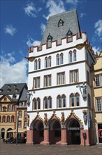 Medieval white and red building with ornate gables and historical flair in an urban setting, Haus