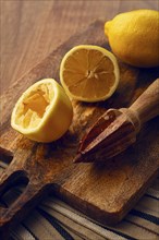 Lemons and a wooden manual citrus juicer, on a chopping board, close-up, no people