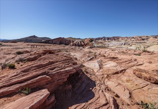 Hikers in the distance along the layered sandstone Fire Wave Trail at Valley of Fire State Park