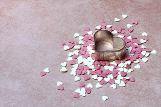 Heart-shaped cookie cutter and sugar hearts on a pink background