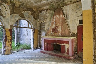 An abandoned historic building with colourful dilapidated walls and a dilapidated fireplace inside,