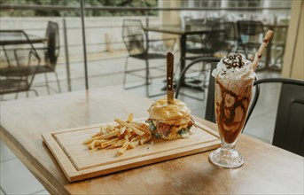 Big hamburger with fries and milkshake on restaurant table. Classic burger with fries and milkshake