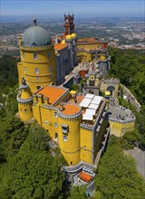 Historic castle in yellow on a hill with an impressive view and surrounded by forest, aerial view,