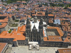 The aerial view captures the cathedral and the red roofs of a historic city, surrounded by stone