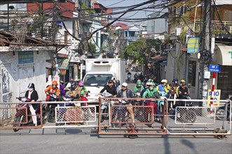 Moped riders waiting at the railway crossing, Hanoi, Vietnam, Asia