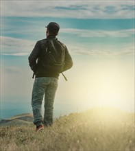 Rear view of backpacker man walking in the mountain. Low angle of backpacker man walking in the