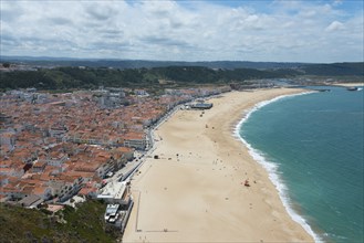 Beach with city in the background and extensive coastline, blue sea and soft clouds in the sky,