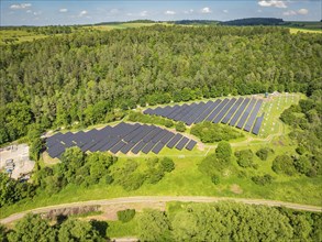 Aerial view of a large solar panel farm, surrounded by forest and fields, construction of the Black