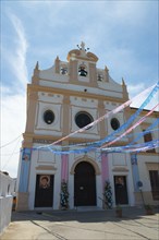 Front view of a decorated church with bell tower and colourful flags on a sunny day, Santuario de