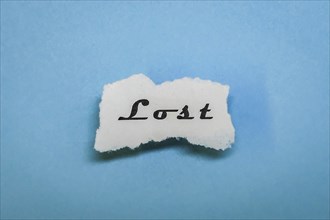 A piece of paper with the word 'Lost' on a blue background, minimalist